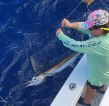client holds the leader on a white marlin by the boat, he also caught a sailfish