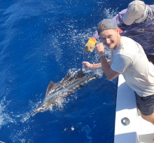SGU students holds the leader on a sailfish by the boat
