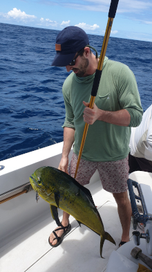 client with dorado on the gaff in the boat